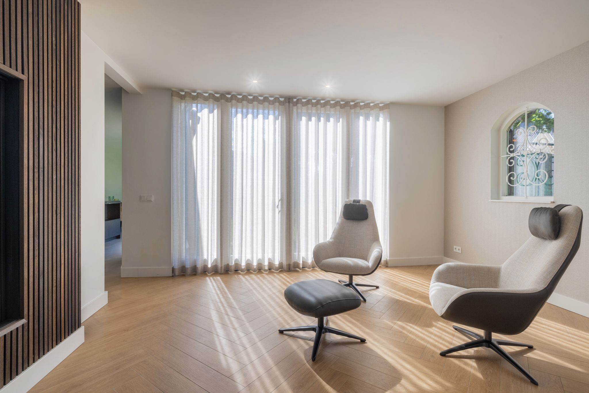 moderne-zithoek-met-designfauteuils,-visgraatvloer-en-zachte-raambekleding.jpg